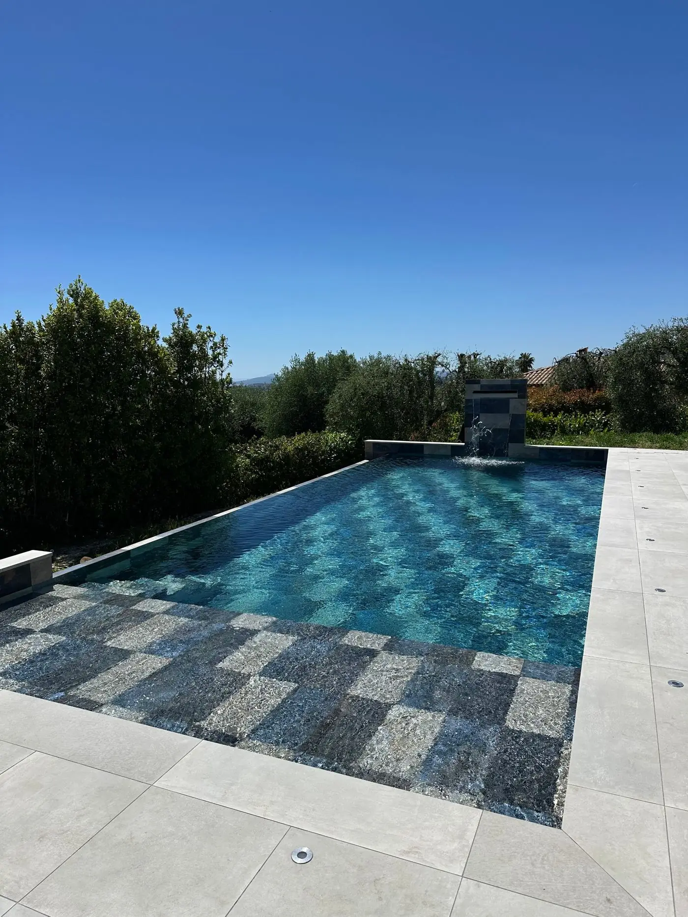 Piscine en pierre de Bali avec cascade, dans un jardin d'oliviers